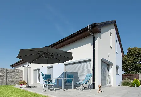 Rodinný dům s venkovními roletami a terasou se zahradním posezením